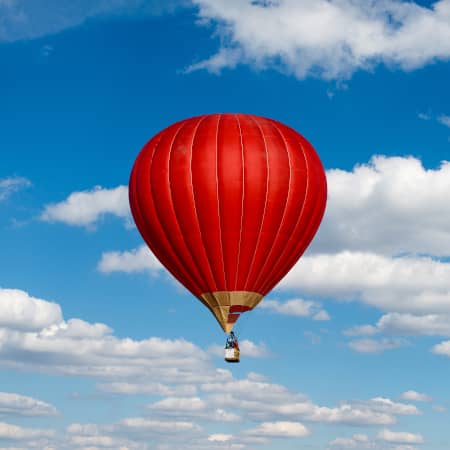 Red hot air balloon in a cloudy sky