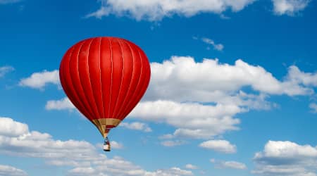 Red hot air balloon in a cloudy sky